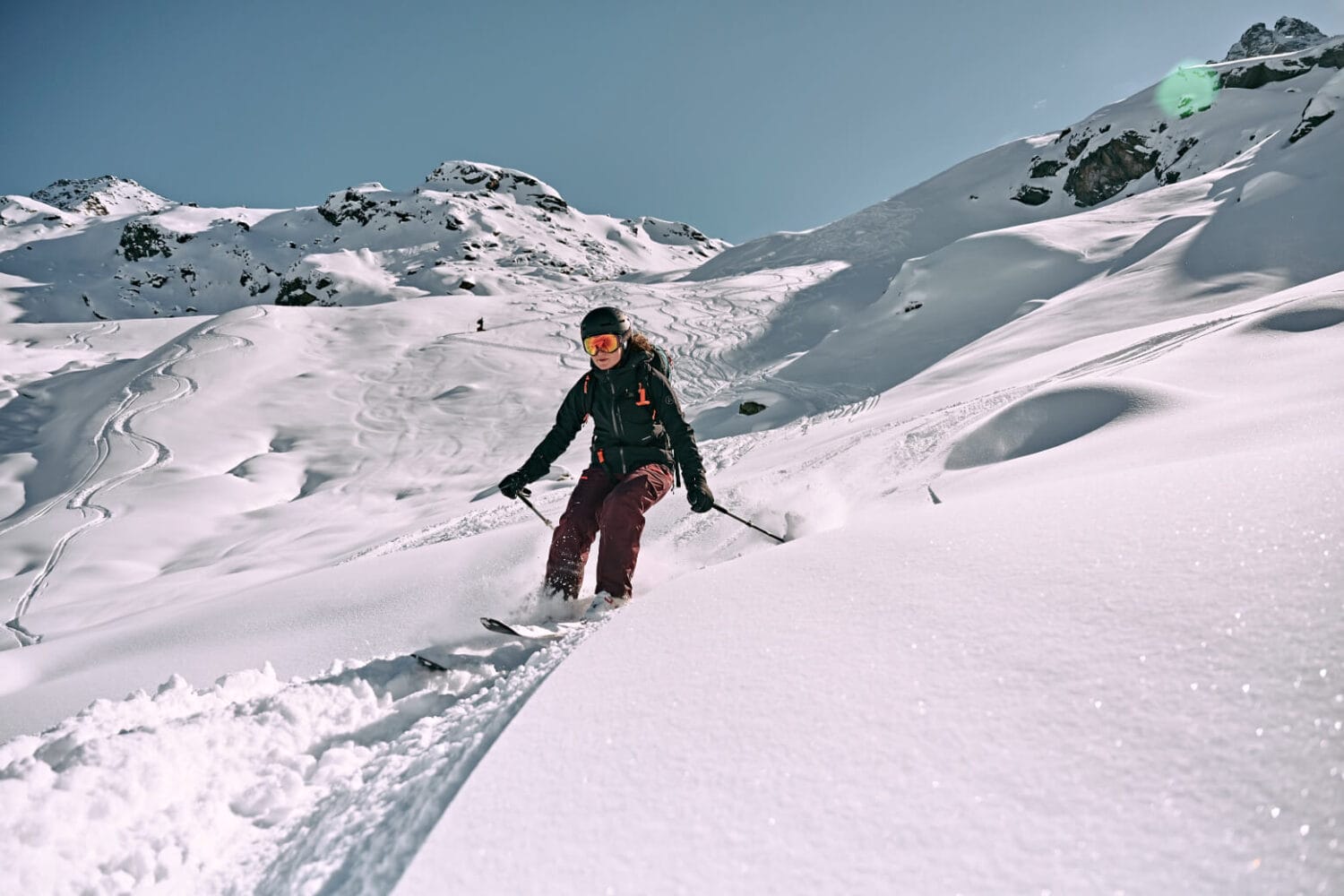 Skifahrerin im Tiefschnee, Bergpanorama im Hintergrund