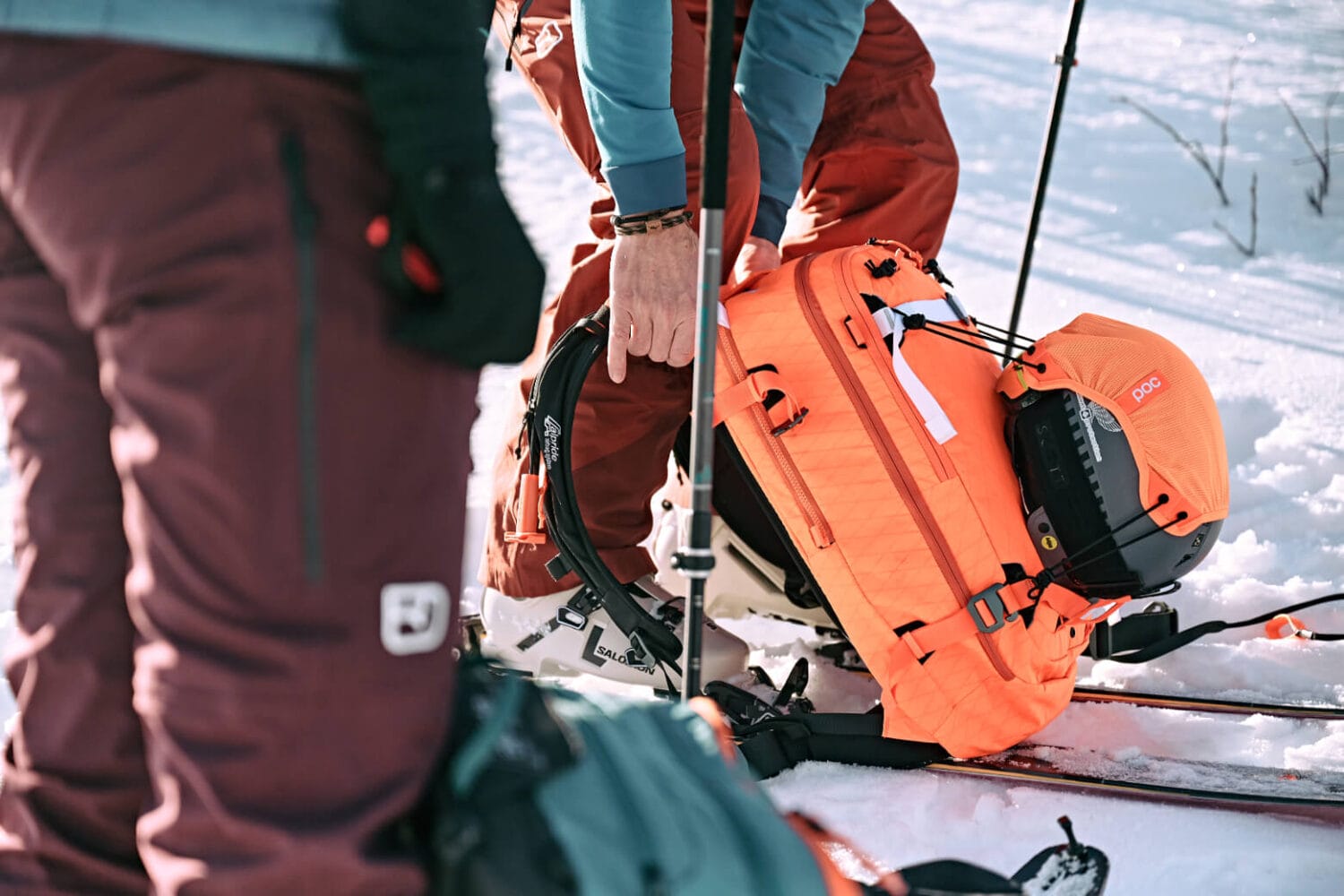 ein orangener Skirucksack mit Airbag System steht auf eine Skipiste und wird geöffnet